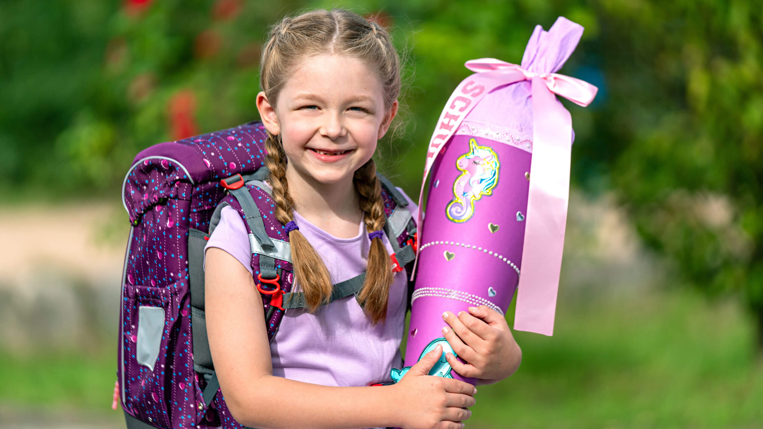 Schulanfängerin mit Ranzen und Schulüte in lila/pink