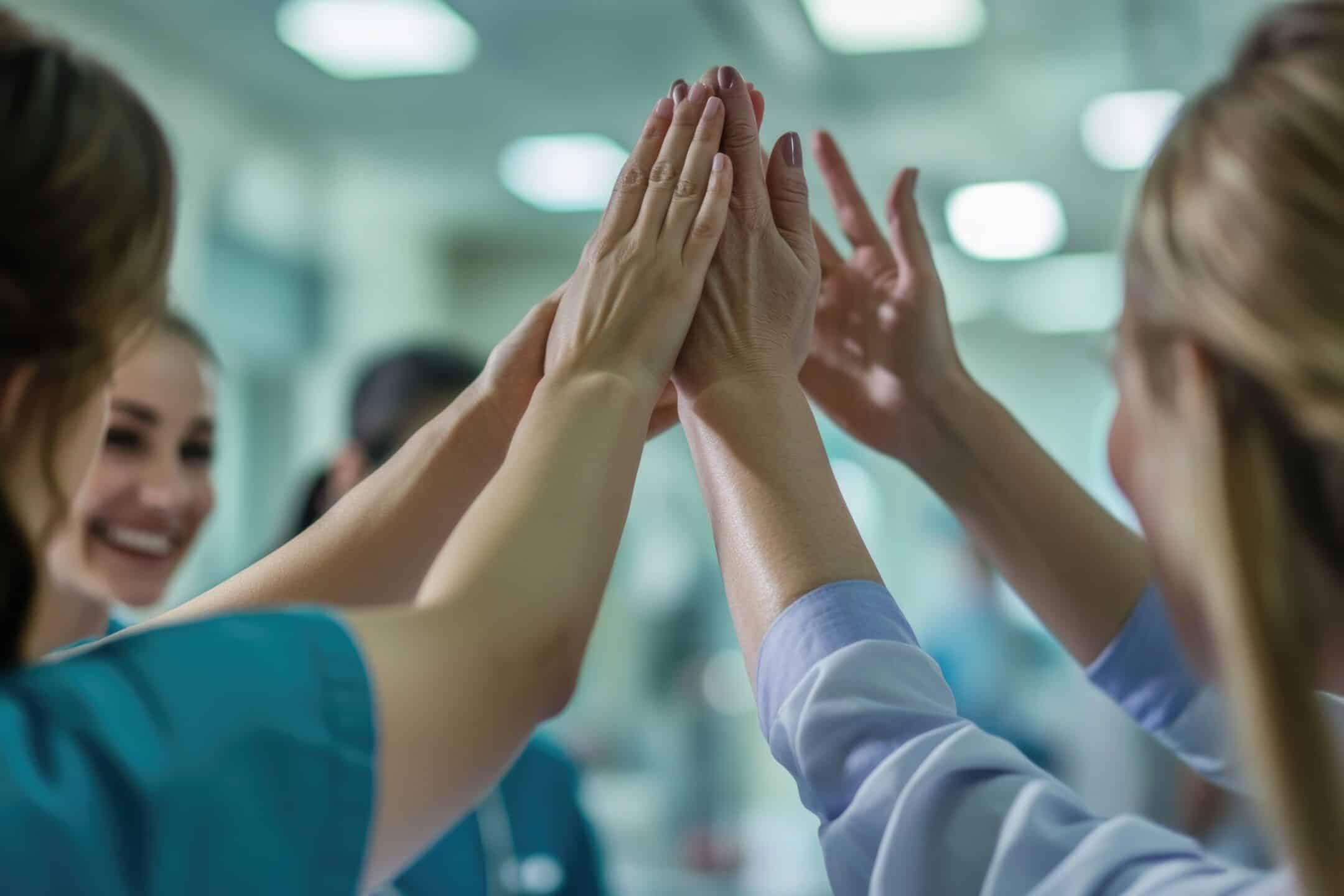 A group of nurses lifting hands in celebration, conveying teamwork and camaraderie.