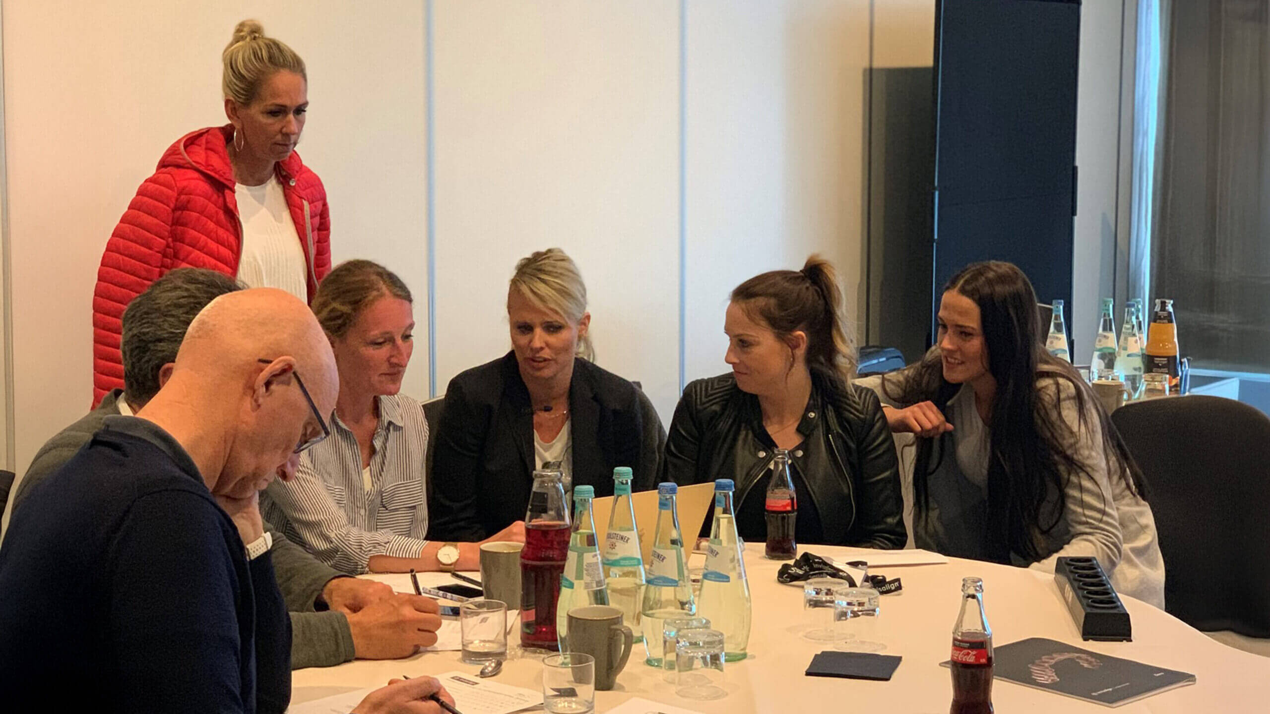 Menschen an einem runden Tisch auf den Bildschirm schauend